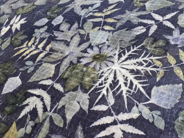 People holding a large fabric with botanical prints