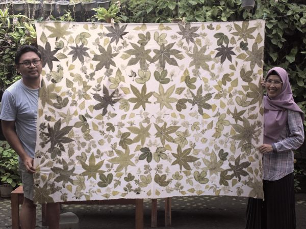 People holding a large fabric with botanical prints
