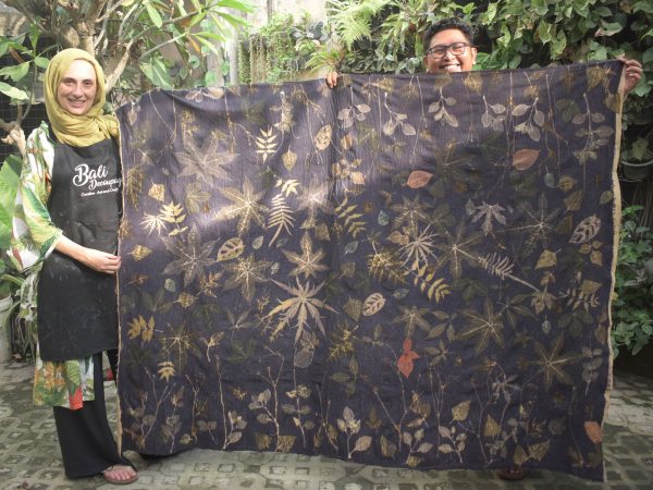 People holding a large fabric with botanical prints